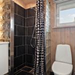Badezimmer mit Dusche, Toilette und Waschbecken. Holzwände und Glasblockwand.