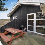 Terrasse mit Picknicktisch, Grill und Glastür zur Unterkunft.