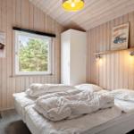 Schlafzimmer mit Holzwänden, Bett, Fenster und Stuhl.