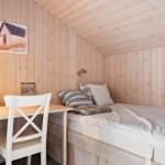 Ein Schlafzimmer mit Bett, Schreibtisch und Wandbild. Holzwände und Decke.
