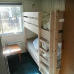 Zimmer mit Doppelstockbett, kleinem Tisch und Fenster mit Blick nach draußen.