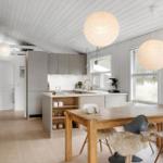 Küche und Essbereich mit Holztisch, grauen Schränken und runden Lampen.