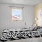 Schlafzimmer mit Bett, Fenster und Wandbild. Holzwände und Streifenbezug.