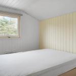 Ein Schlafzimmer mit einem Bett und einem Fenster mit Blick auf Bäume.