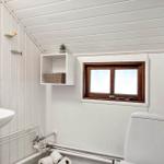 Bathroom with sink, toilet, and window with wooden frame.