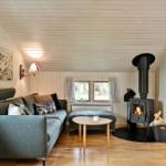 Living room with sofa, wood stove, and hardwood floor. A TV is mounted on the wall.