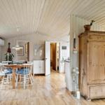 A room with dining area, hardwood floor, and antique wardrobe. A guitar hangs on the wall.