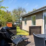 Terrasse mit Liegen, Tisch und Grill. Hinterhof mit Grünfläche und Bäumen.