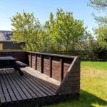 Holzterrasse mit Picknicktisch und Grünfläche im Hintergrund.