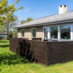 Haus mit Holzterrasse und großem Fensterbereich im Garten.