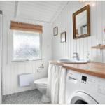 Badezimmer mit Waschmaschine, Spiegel und Fenster mit Rollladen.