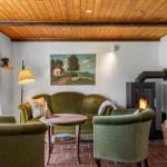 Living room with green chairs, fireplace, and wooden ceiling.