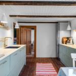 Kitchen with light cabinets, red floor, and wooden beams on the ceiling.