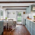Kitchen and dining area with wooden floor, light cabinets, and window to the garden.