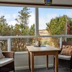 A table with two chairs in front of large windows with a view of trees and a flag.