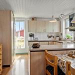 Kitchen with wooden furniture, countertop, and window view of outdoor area.