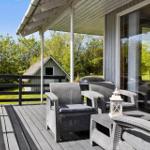 Terrasse mit Gartenmöbeln, Grill und Blick auf einen kleinen Garten.