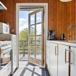 Küche mit Holzwand, Tür zum Balkon und Küchengeräten.