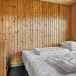 Schlafzimmer mit Holzwand, Bett und Fenster