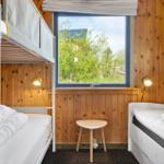 Zimmer mit Etagenbett, Einzelbett und Fensterblick auf Grünflächen.