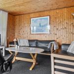 Wohnzimmer mit Holzwänden, Sofa, Couchtisch und Fenster. Wandbild zeigt Windmühle.