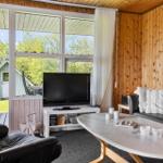 Wohnzimmer mit Sofa, Fernseher und großem Fensterblick auf Garten.