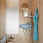 Bathroom with wooden walls, blue sink, and mirror