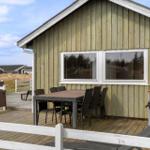 Deck with table, chairs, and grill beside wooden houses
