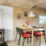 Dining area with table, chairs, and wood stove against white brick wall.