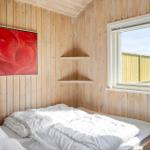 Bedroom with wooden walls, bed, and window. A painting hangs on the wall.