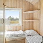Bedroom with wooden walls, window, and mattress.