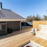 Holzterrasse mit Sitzbank, Grill und Blick auf Bäume.