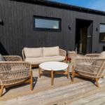 Terrasse mit Sitzgruppe und Tisch vor einem schwarzen Holzhaus