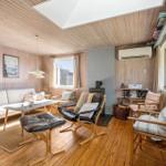 Wohnzimmer mit Holzwand, Sofa, Sessel und Kamin.