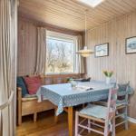 Esszimmer mit Holzwand, Tisch, Stühlen und Fensterblick auf Grünflächen.
