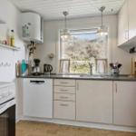 Küche mit Fenster, Spüle, Kühlschrank und Kochgeräten.