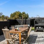 Holztisch mit Stühlen, Whirlpool und Grillbereich auf Holzterrasse.