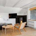 Wohnzimmer mit Sofa, Fernseher und Kamin. Holzfußboden und weiße Wände.