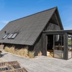 Moderne Holzhütte mit großem Holzterrasse und Glasveranda. Außentisch mit Stühlen.