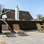 Terrasse mit Liegestühlen und Tisch. Hintergrund: Holzhaus mit Schornstein.