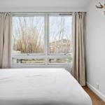 Schlafzimmer mit Bett, Fenster und Vorhängen. Wanddekoration mit Hirschgeweih.