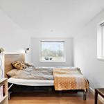 Schlafzimmer mit Bett, Fenstern und Holzboden.