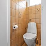 Toilette mit braunen Fliesen und Toilettenpapierhalter