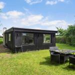 Schwarzes Holzhaus mit Garten, Sitzgruppe und Grill. Hinterhof mit Bäumen.