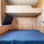 A bedroom with a bed, wall-mounted TV, and climbing wall on the wall.