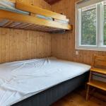 Room with double bed, sofa bed, and wooden window with view of trees.
