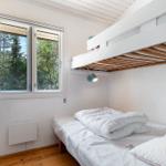 Room with double bed, loft bed, and window to the forest