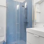 Bathroom with shower, sink and toilet. Tiles in blue and white.