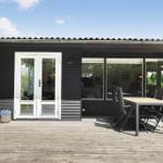 Modern villa with terrace, table and chairs. Large windows and white door.