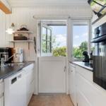 Kitchen with white cabinets, stainless steel sink, and view of green outdoor areas.